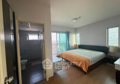 Spacious bedroom with ensuite bathroom and balcony view in modern apartment.