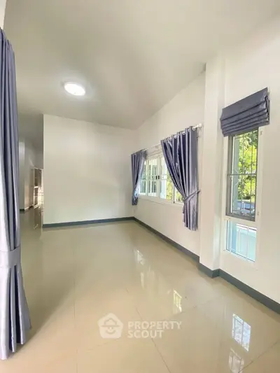 Spacious and bright room with large windows and elegant curtains