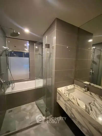 Luxurious modern bathroom with marble sink and glass shower enclosure.