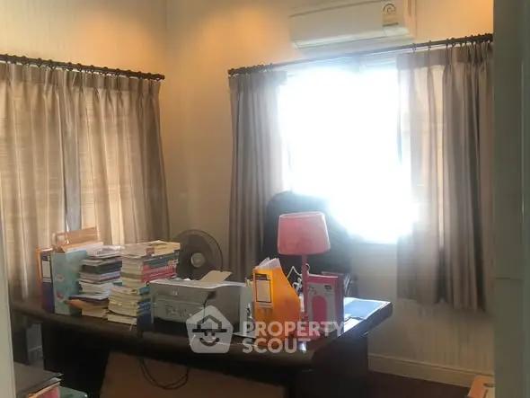 Cozy study room with desk, books, and natural light through window.
