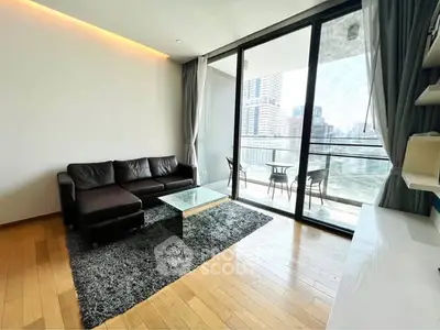 Modern living room with large glass doors leading to a balcony with city views, featuring a sleek black sofa and stylish decor.