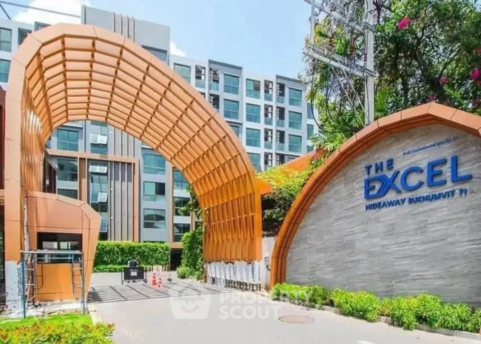 Modern apartment building entrance with unique architectural design and lush greenery.