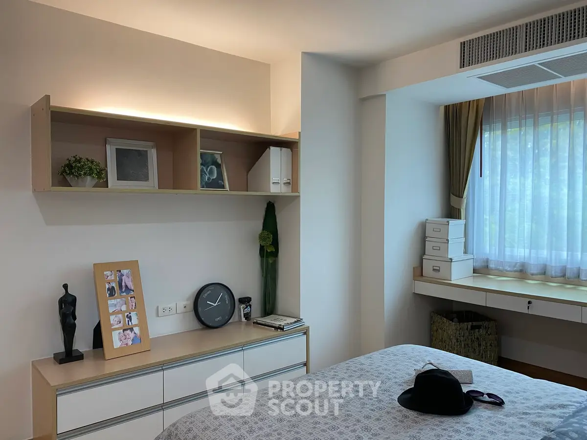 Cozy bedroom with modern decor, featuring a stylish shelf and a large window for natural light.