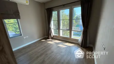 Sunlit spacious room with large windows and hardwood flooring, ideal for a comfortable living space with a view.