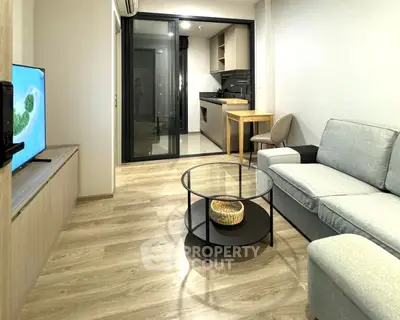 Modern living room with open kitchen, stylish furniture, and wooden flooring.