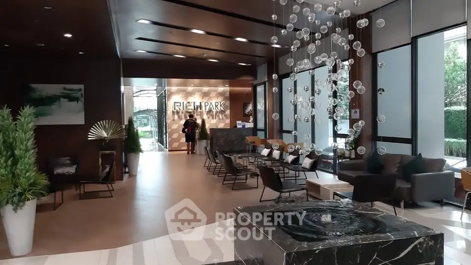 Luxurious modern lobby with elegant seating and stunning chandelier in upscale building.