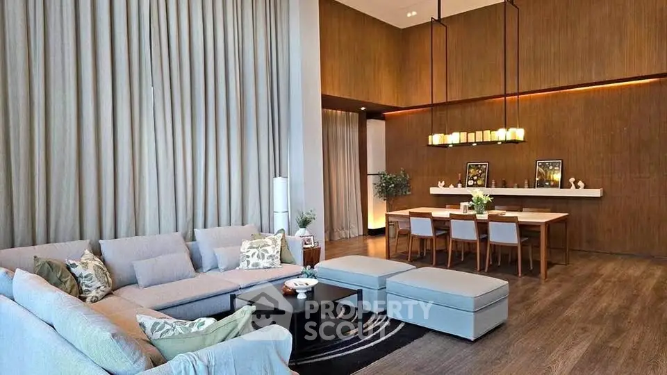 Luxurious living room with high ceilings and elegant decor, featuring a spacious seating area and stylish dining setup.