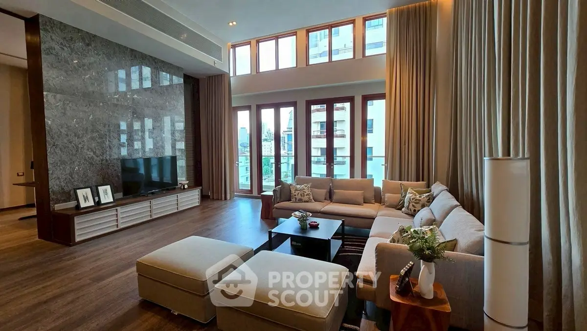 Luxurious living room with high ceilings, elegant decor, and large windows offering natural light and city views.