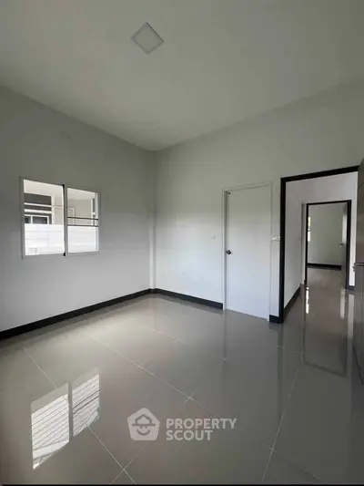 Spacious empty room with glossy tiled floor and white walls, perfect for customization.