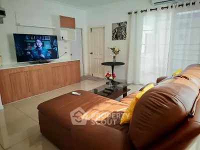 Spacious living room with modern decor and large TV, perfect for relaxation and entertainment.