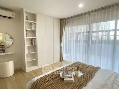 Modern bedroom with large window and stylish decor, featuring a cozy bed and built-in storage.