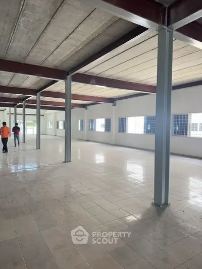 Spacious industrial warehouse interior with tiled flooring and ample natural light.