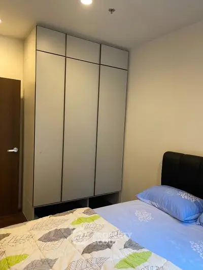 Modern bedroom with sleek wardrobe and cozy bedding in a stylish apartment.