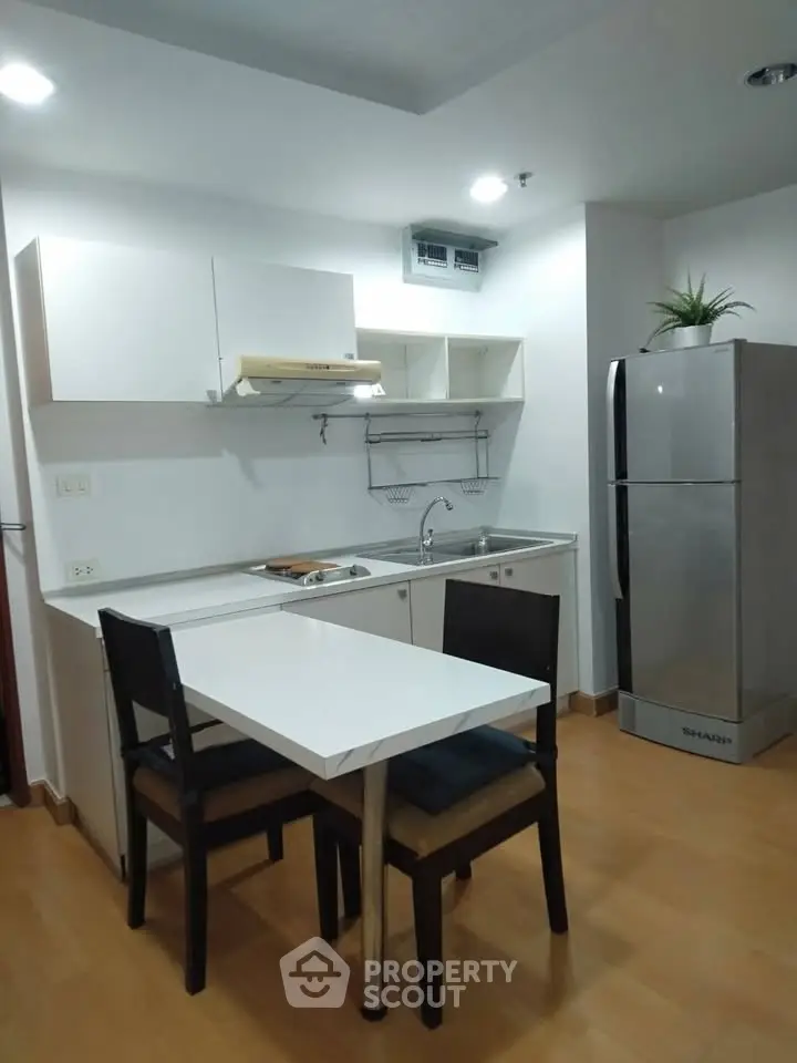 Modern kitchen with sleek design, featuring a compact dining area and stainless steel appliances.
