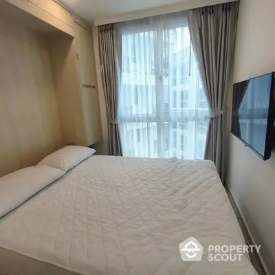 Modern bedroom with large window and wall-mounted TV in a high-rise apartment.