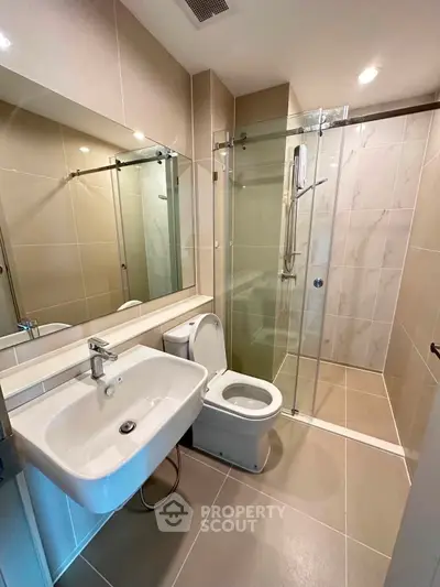 Modern bathroom with glass shower enclosure and sleek fixtures in a contemporary apartment.