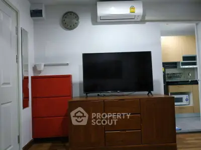 Modern living room with TV, air conditioning, and stylish red cabinet in a cozy apartment.