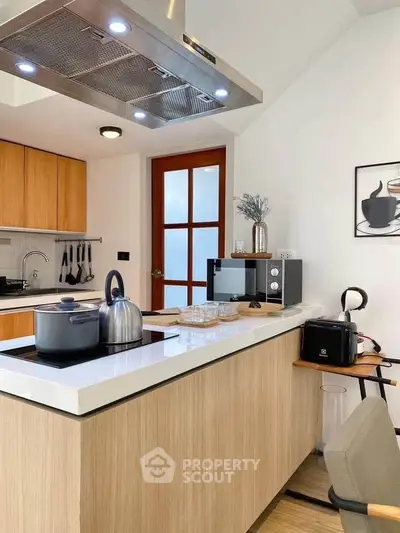Modern kitchen with sleek island, wooden cabinets, and stainless steel appliances in a stylish home.