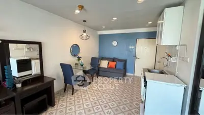 Charming living room with modern decor and open kitchen layout, featuring stylish blue accents and cozy seating.