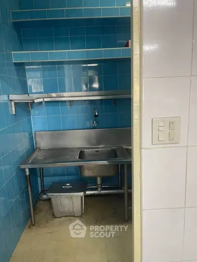 Compact kitchen with blue tiles and stainless steel sink