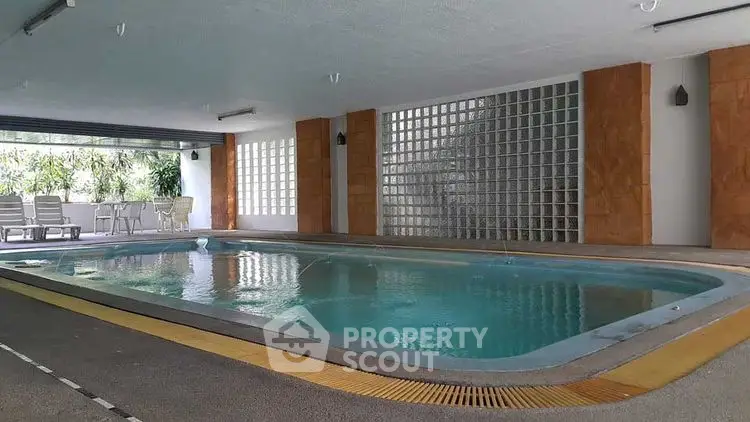 Luxurious indoor pool area with modern design and seating, perfect for relaxation and leisure.