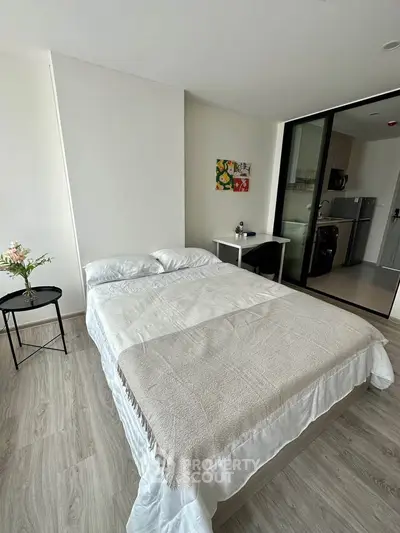 Modern bedroom with cozy bed and open kitchen view