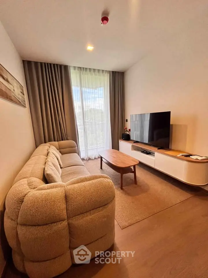 Cozy living room with plush sofa, modern TV setup, and large window with curtains.