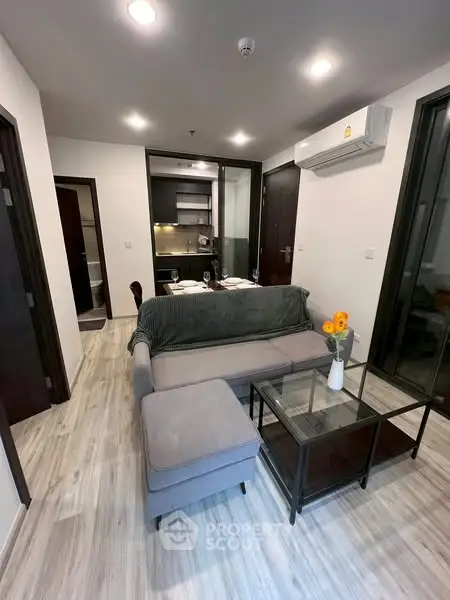 Modern living room with cozy seating and open kitchen layout in stylish apartment.