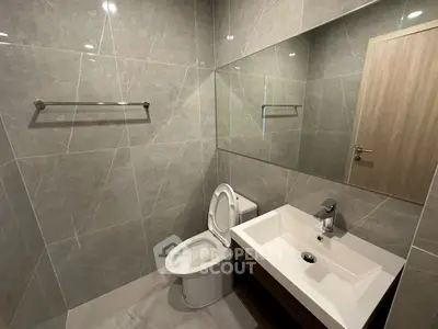 Modern bathroom with sleek design, featuring a large mirror and elegant fixtures.
