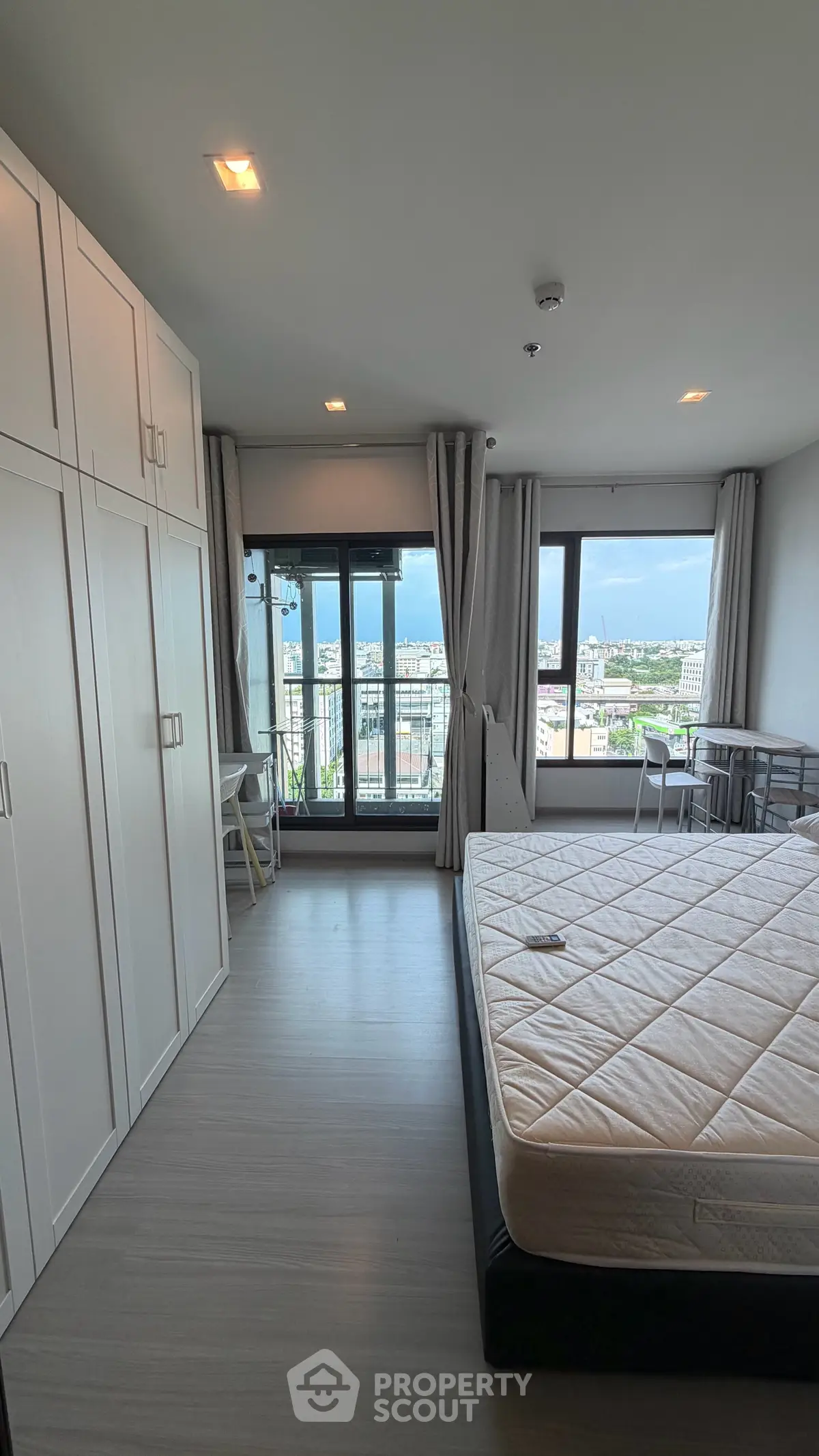 Spacious bedroom with large windows offering stunning city views, ample storage, and modern furnishings.