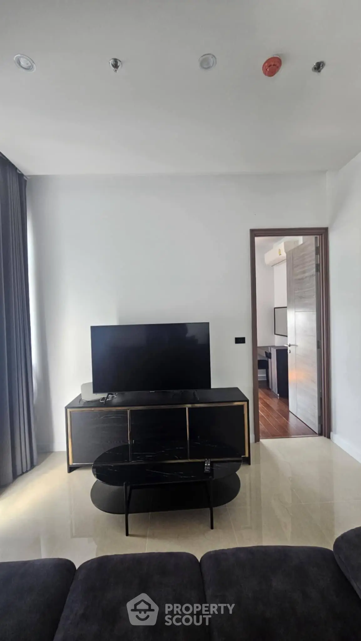Modern living room with sleek TV stand and large flat-screen TV, featuring elegant decor and natural light.