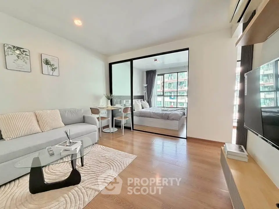 Modern open-plan living room with stylish decor and cozy bedroom view, perfect for urban living.