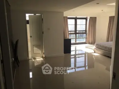 Spacious bedroom with large windows and glossy tiled floors in modern apartment.