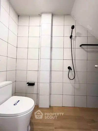 Modern minimalist bathroom with white tiles and sleek black fixtures.