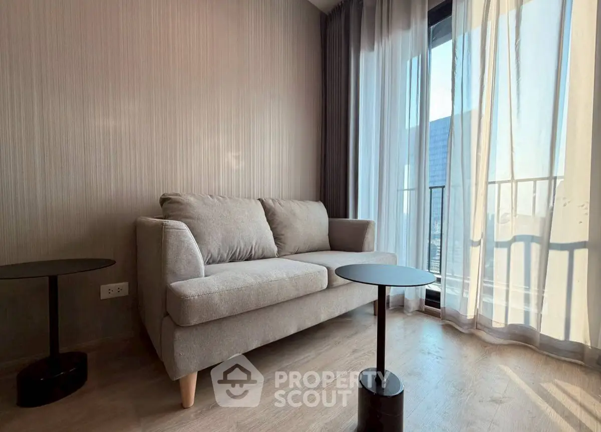 Modern living room with cozy sofa and floor-to-ceiling windows offering natural light.