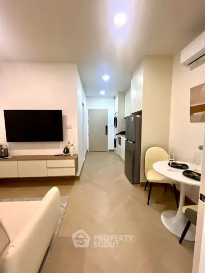 Modern living room with sleek furniture and integrated kitchen appliances in a cozy apartment.