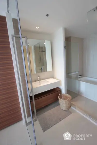 Modern bathroom with sleek design, featuring a glass shower, large mirror, and wooden vanity for a touch of warmth in a contemporary home.