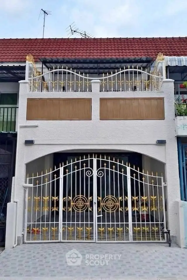 Charming townhouse with ornate wrought iron gate and balcony, featuring a classic red-tiled roof.
