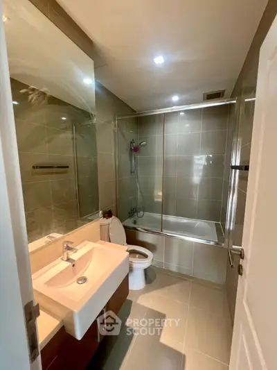 Modern bathroom with sleek fixtures and glass shower enclosure in a contemporary apartment.