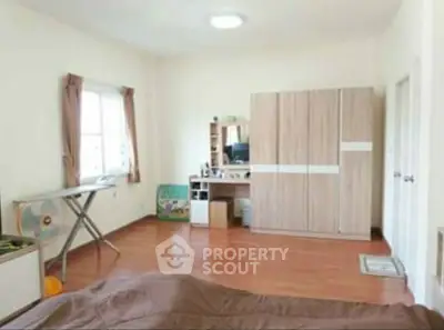 Spacious bedroom with wooden flooring and modern furniture