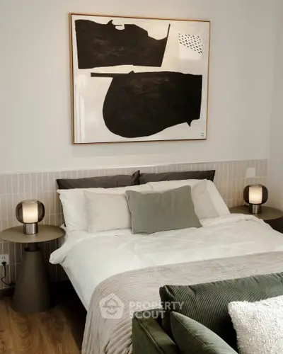 Stylish bedroom with modern decor and abstract art, featuring cozy bedding and ambient lighting.