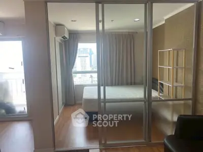 Modern bedroom with glass sliding doors and city view, featuring elegant decor and natural light.