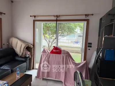 Cozy living room with sliding glass doors leading to a garden view, featuring comfortable seating and modern decor.