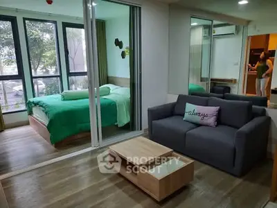 Modern studio apartment with cozy living area and bedroom separated by glass doors.