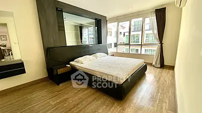 Spacious modern bedroom with large windows and wooden flooring