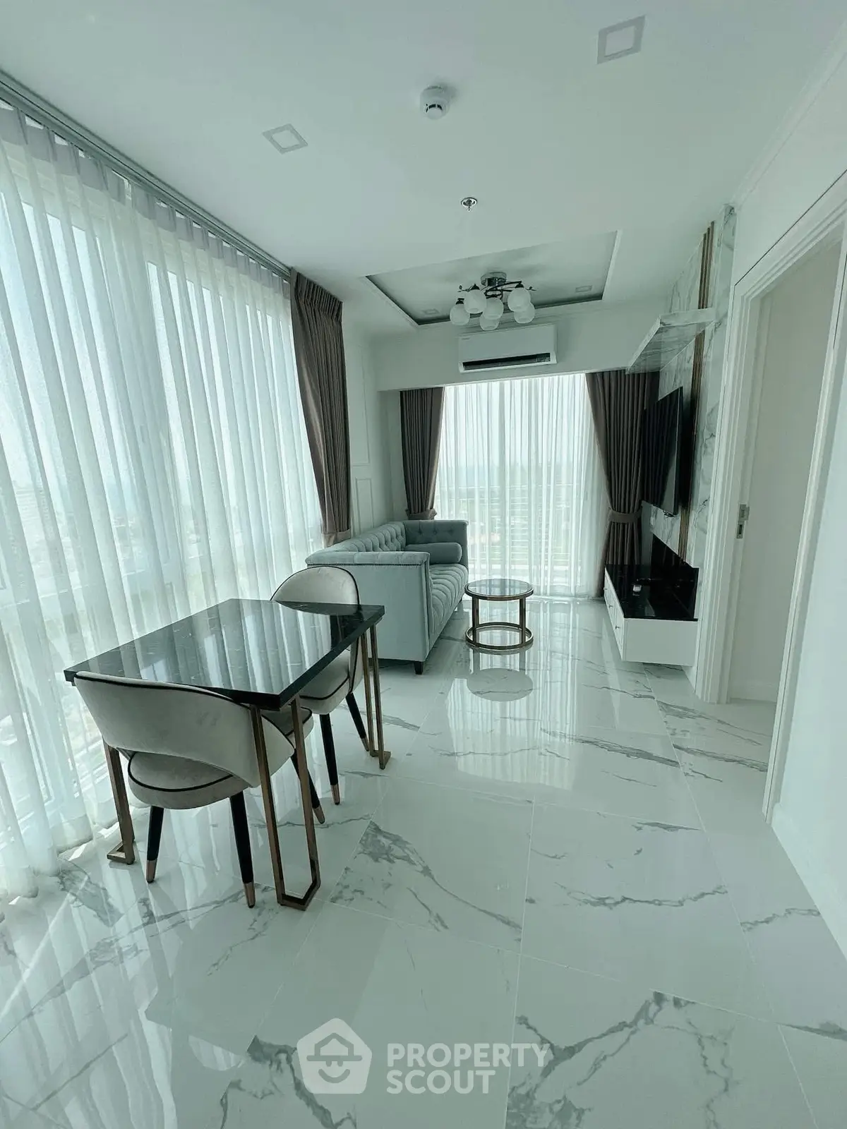 Modern living room with marble flooring and large windows offering natural light.