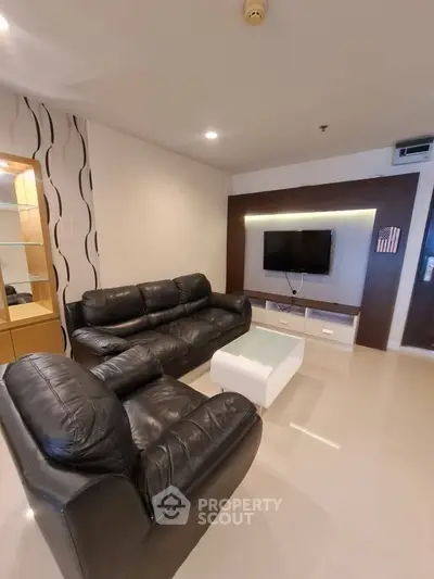 Modern living room with sleek leather sofas and wall-mounted TV in a stylish apartment.