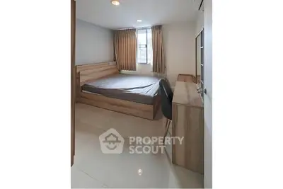 Modern bedroom with sleek wooden furniture and large window for natural light.