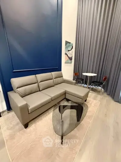 Modern living room with stylish gray sectional sofa and elegant glass coffee table.