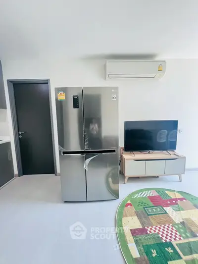Modern living room with stainless steel fridge, TV, and air conditioning unit.